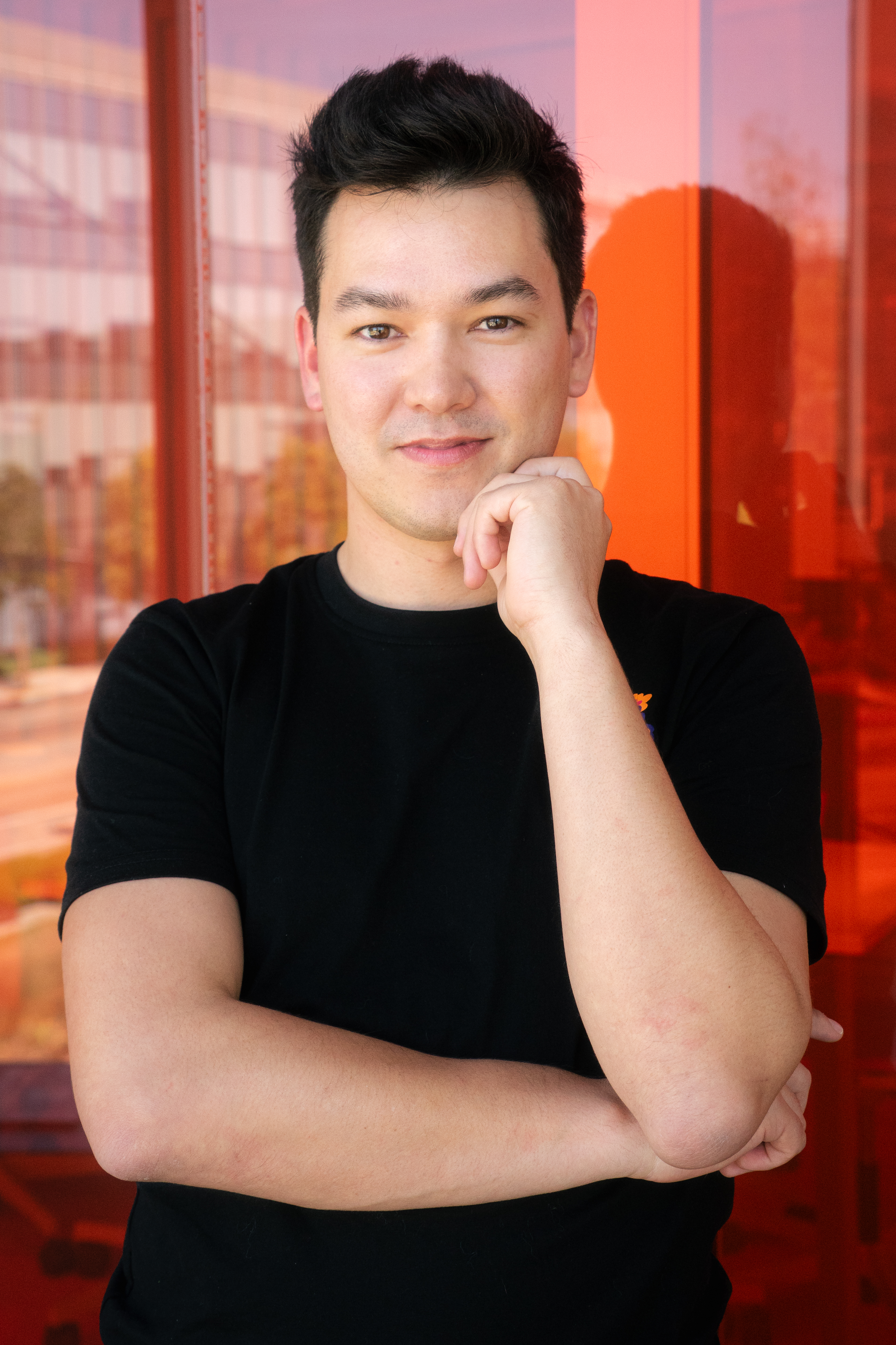 Young man with dark hair posing with his hand on his chin