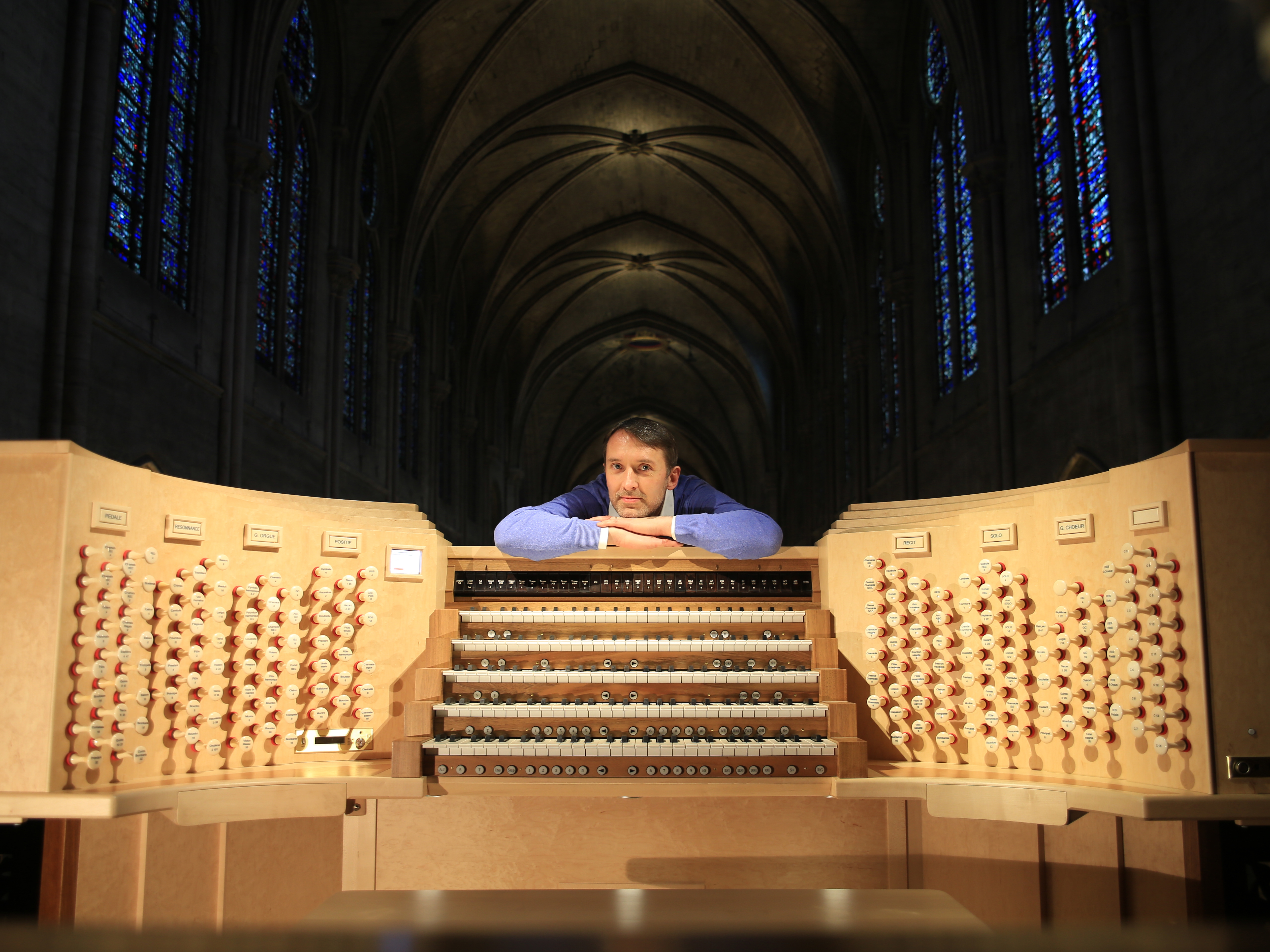 Olivier Latry, Notre Dame's longest-serving organist, poses beside the refurbished instrument, ready for the reopening ceremonies after the destructive fire in 2019.