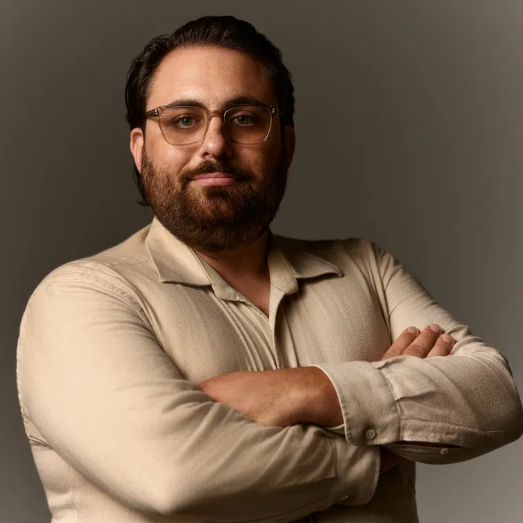 Man with glasses and a short beard in a light colored shirt